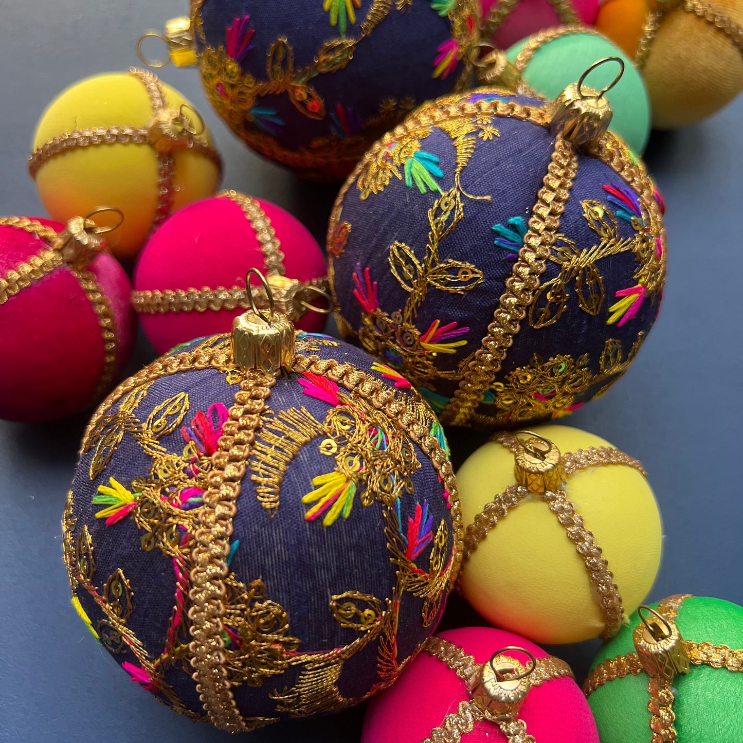 Aasha deep blue embroidered baubles with gold detailing and colourful accents, luxury handmade sustainable Christmas ornaments displayed in a vibrant festive setting