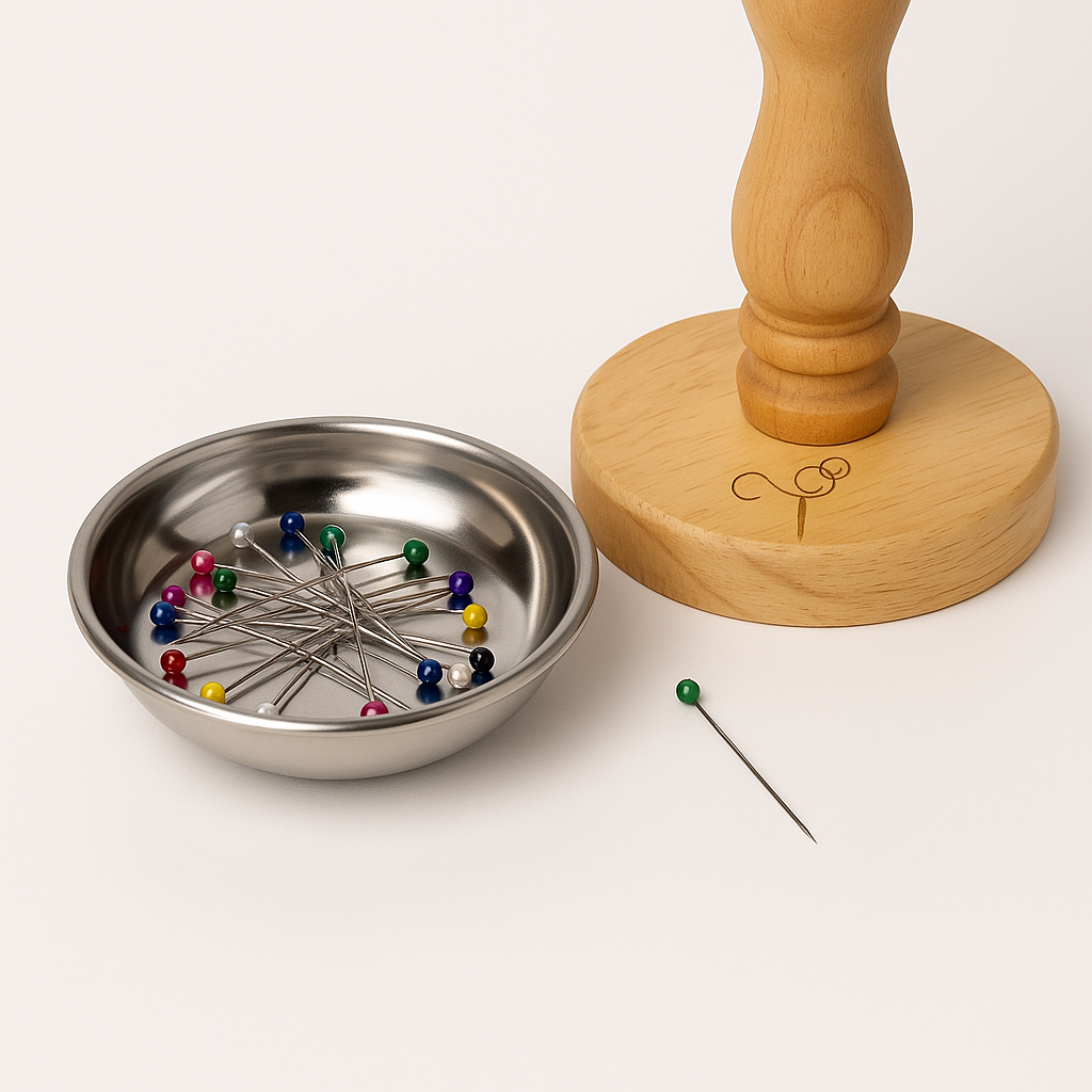 Magnetic pin bowl filled with colourful dressmaking pins next to the Mashquin base, showing part of the Marisha Mistry logo.