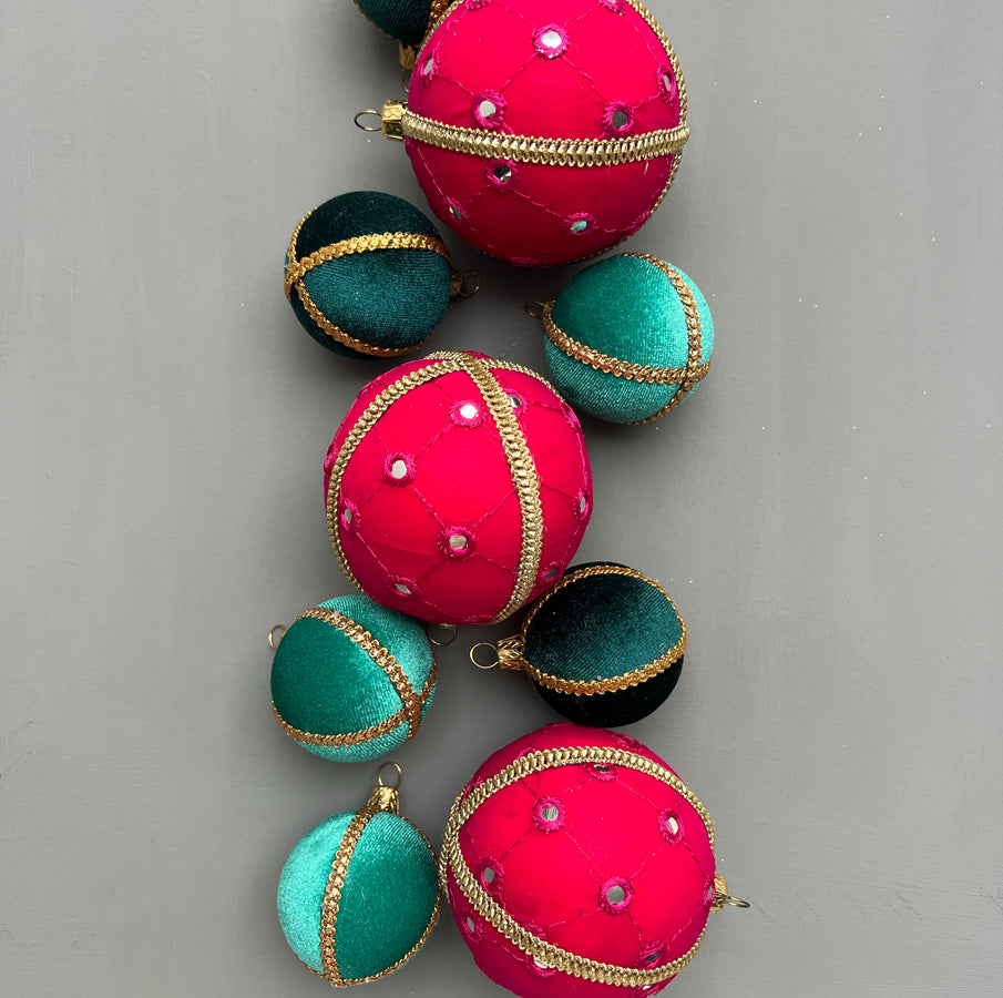Flat lay of Salina Baubles in hot pink with mirror accents, mixed with teal velvet baubles on a soft grey background for a playful modern look.