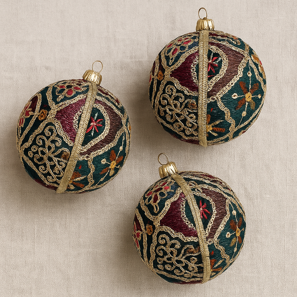 Three ornate Christmas ornaments with intricate patterns on a beige fabric background