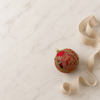 Close-up of the Aarna bauble showing sweeping gold zari cord goldwork in paisley and floral forms with dense gold sequins on hot pink reclaimed fabric.