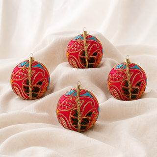 A cluster of Aditi handmade fabric baubles, 10cm, grouped to show the large sweeping gold paisley cordwork with dense magenta satin stitch and multicolour panels.