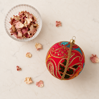 Aditi bauble detail shot, a 10cm UK-made sustainable ornament with hot pink ground and large sweeping gold paisley cordwork with dense magenta satin stitch and multicolour panels.