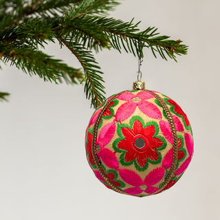 Advik handmade fabric bauble on a marble surface, 10cm, showing large-scale hand-embroidered daisy and sunflower motifs with shisha mirror centres on a warm cream ground.