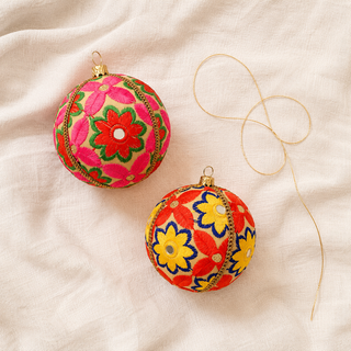 Advik fabric bauble styled on linen, a 10cm handmade ornament with large-scale hand-embroidered daisy and sunflower motifs with shisha mirror centres.