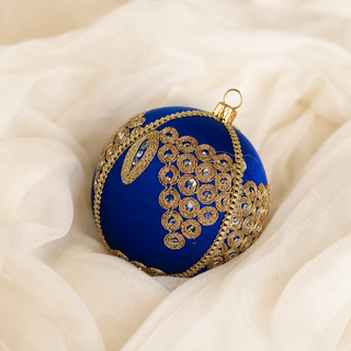 Close-up of the Arjun bauble showing a cascading cluster of gold mirror-work medallions with an elongated leaf motif on royal blue reclaimed fabric.