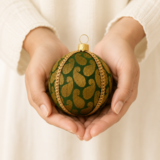 Close-up of the Charu bauble showing a bold gold woven paisley brocade with a gold chain braid trim on forest green reclaimed fabric.