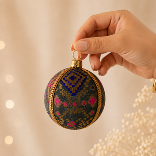 Chirag fabric bauble held in hand, highlighting the scale and sustainable, reclaimed-textile craftsmanship of this 8cm bauble.