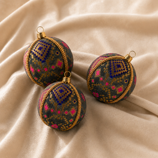 Close-up of the Chirag bauble showing a dense gold checkerboard pattern lifted by magenta and cobalt blue accents on charcoal reclaimed fabric.