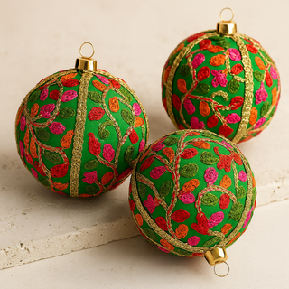 Three green Devaki baubles Christmas ornaments with floral patterns on a light background