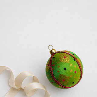 Jaya fabric bauble held in hand, highlighting the scale and sustainable, reclaimed-textile craftsmanship of this 8cm bauble.