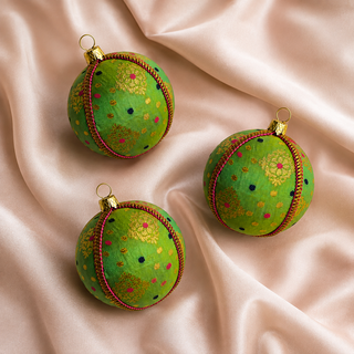 Close-up of the Jaya bauble showing gold diamond-lattice motifs with playful pink and navy dots on vivid green reclaimed fabric.