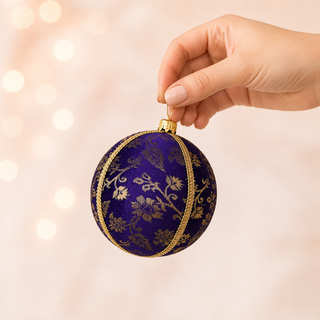 Kaasni fabric bauble held in hand, highlighting the scale and sustainable, reclaimed-textile craftsmanship of this 8cm bauble.