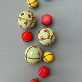 flat lay Kalinda baubles on a grey background and pops of mini yellow and red baubles. 