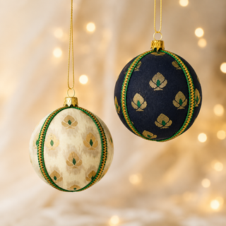 Close-up of the Kamla bauble showing a delicate gold floral motif with green accents and a green-and-gold cord trim on soft cream (also in black) reclaimed fabric.