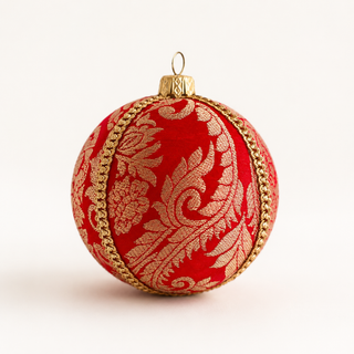 A round red Christmas ornament with a gold damask pattern and gold beaded trim, featuring a gold hanging loop at the top, set against a plain white background.