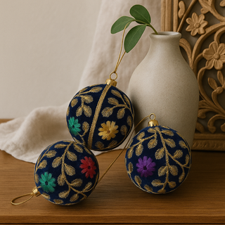 Decorative Mahir spherical ornaments with floral patterns on a wooden surface with a vase in the background.