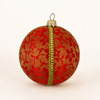 A spherical Christmas ornament wrapped in red floral lace over a gold mesh background, with a vertical gold glitter trim down the center and a gold hanging loop at the top, shown on a plain light background.