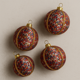 Four patterned Sahanah Christmas ornaments on a beige background