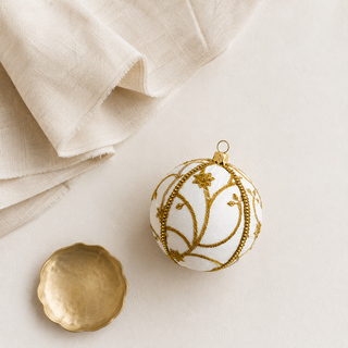 Close-up of the Shashi bauble showing raised gold zardozi embroidery in a sweeping vine and trellis pattern with beaded flowers on ivory reclaimed fabric.