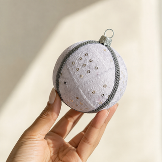A cluster of Snow Queen handmade fabric baubles, 10cm, grouped to show the diamond-quilted stitch pattern with delicate starburst embroidery, scattered sequins and a silver cord trim.