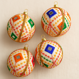 Four embroidered Christmas ornaments with colorful patterns on a beige background