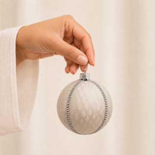 Surya fabric bauble held in hand, highlighting the scale and sustainable, reclaimed-textile craftsmanship of this 8cm bauble.