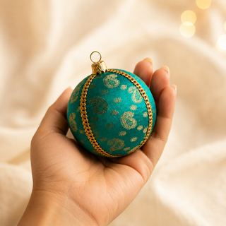 Tarla fabric bauble held in hand, highlighting the scale and sustainable, reclaimed-textile craftsmanship of this 8cm bauble.