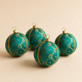 Tarla bauble detail shot, an 8cm UK-made sustainable ornament with deep teal ground and gold paisley motifs and delicate dotted brocade with a gold cord seam trim.