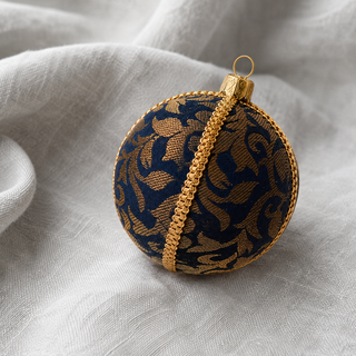 Close-up of the Vani bauble showing sweeping gold floral scrollwork woven throughout with a gold cord seam trim on navy reclaimed fabric.