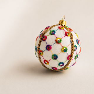 Vikram handmade fabric bauble, 8cm, cream ground with a lattice of coloured thread with rainbow stitched circles and tiny mirror centres.