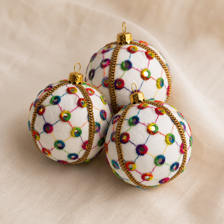 Vikram bauble detail shot, an 8cm UK-made sustainable ornament with cream ground and a lattice of coloured thread with rainbow stitched circles and tiny mirror centres.