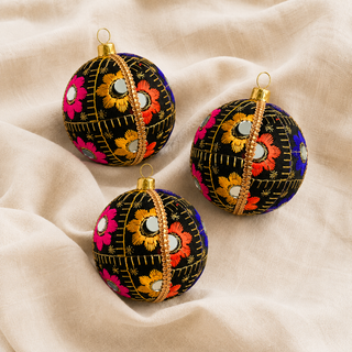 A cluster of Vimal handmade fabric baubles, 8cm, grouped to show the bursts of gold, orange, pink and blue floral embroidery with mirror discs and gold quilted stitch lines.