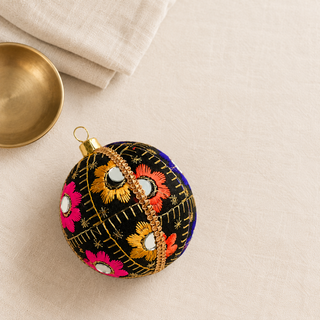 Close-up of the Vimal bauble showing bursts of gold, orange, pink and blue floral embroidery with mirror discs and gold quilted stitch lines on black reclaimed fabric.