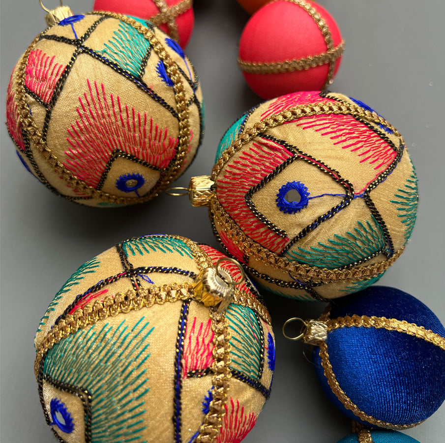 Aarav Baubles in 8cm laid out on a soft grey background alongside other colourful designs, showing close-up thread detail, gold trim, and mirror-style accents.