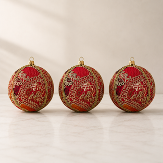 Aarna bauble hanging with soft bokeh lights, showing its hot pink ground and sweeping gold zari cord goldwork in paisley and floral forms with dense gold sequins.