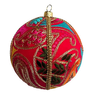 A close-up of a vibrant cluster of fabric baubles on a blue background, with three Aditi Baubles in bright pink, teal, and gold embroidery standing out boldly.
