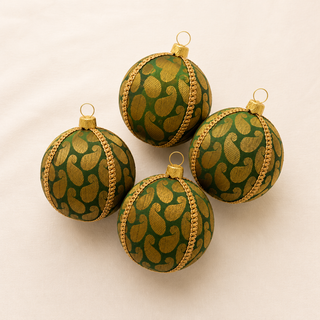 Charu bauble hanging with soft bokeh lights, showing its forest green ground and a bold gold woven paisley brocade with a gold chain braid trim.