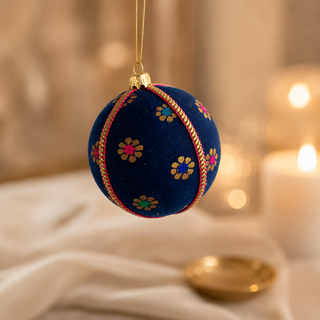 Dancing Florals fabric bauble styled on linen, an 8cm handmade ornament with scattered gold flower motifs with jewel-tone pink, green and blue centres.