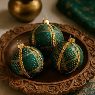 Three Diya Baubles resting in a carved wooden tray with a brass pot and teal brocade fabric, styled with warm Indian elegance.