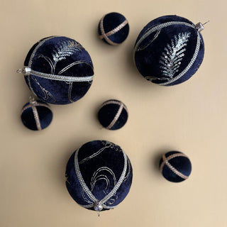 Flat lay of Kaia Baubles in 10cm with black velvet and gold sequin embroidery, styled alongside other black velvet baubles on a soft beige background.