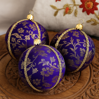 Kansi Baubles resting in a carved wooden tray with an embroidered cushion in the background, styled with subtle Indian accents.