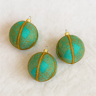 Close-up of Lakshmanji Bauble showing intricate gold floral brocade on soft blue fabric.