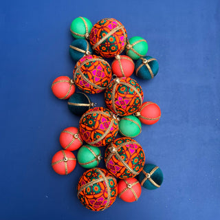 A vibrant cluster of Mahika Baubles in 8cm surrounded by assorted velvet baubles, arranged on a bold blue background for a striking, colourful flat lay.