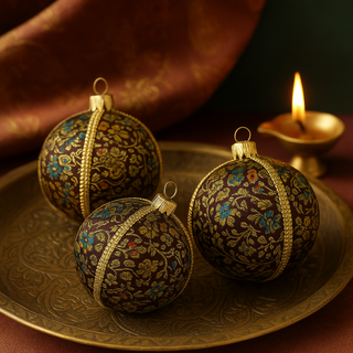 Three Neena Baubles in dark brocade fabric placed on a carved brass tray, styled beside a diya and Indian textile, with all baubles shown at equal 8cm size.