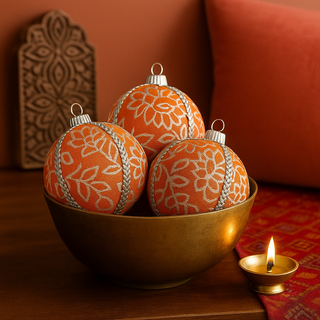 Three Shylah Baubles styled in a home interior with a soft Indian touch — brass detail, carved wood, and warm tones enhancing the festive orange brocade design.