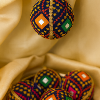 Close-up of Taarush Bauble showing colourful thread embroidery and abla (mirror) detailing.