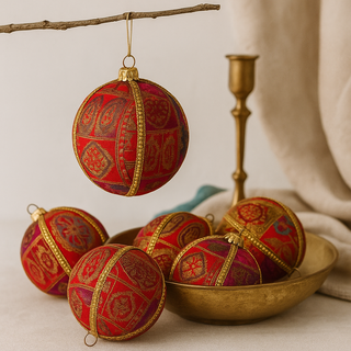 Yashodah Bauble – 10cm silk ornament in reds, pinks, and oranges with intricate woven patterns, handmade in the UK.